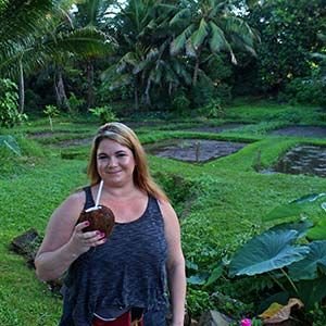 Visitor holding a fresh coconut in a tropical garden on O'ahu